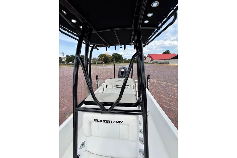 Slide: The Image of 2022 Blazer Bay 2200 boat interior with seating and T-top, parked on brick pavement. - 31