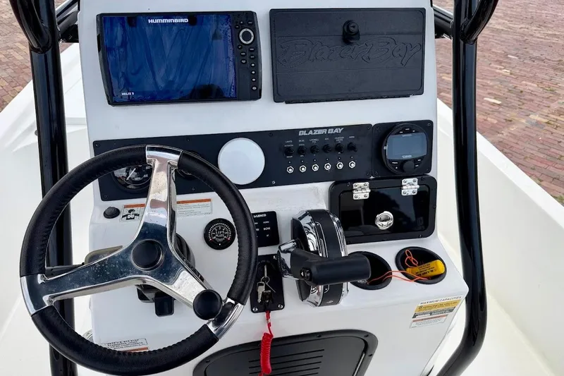 Slide: The Image of 2022 Blazer Bay 2200 boat dashboard with steering wheel and navigation controls. - 35