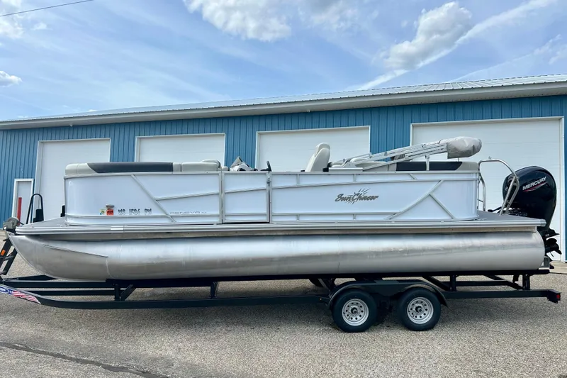 Slide: The Image of 2023 Sun Chaser Geneva pontoon boat on trailer, parked outside blue building. - 18