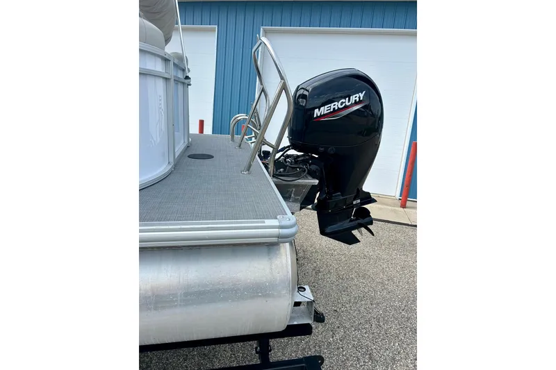 Slide: The Image of 2023 Sun Chaser Geneva boat with Mercury outboard motor, docked near a blue building. - 22