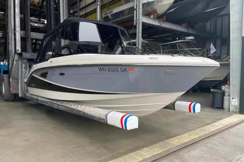 The Image of 2016 Sea Ray SLX 230 boat in storage, featuring sleek design and protective coverings. - 1
