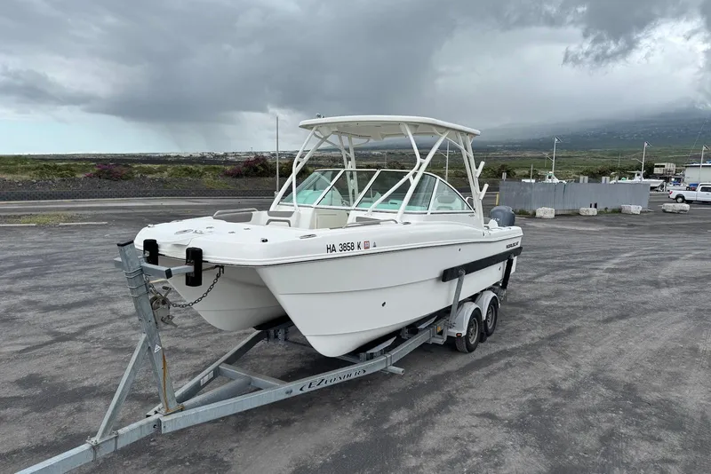 The Image of 2020 World Cat 230 DC boat on trailer, parked under cloudy skies. - 1