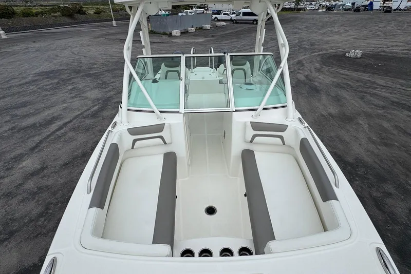 Slide: The Image of 2020 World Cat 230 DC boat interior with seating and windshield, parked on asphalt. - 9