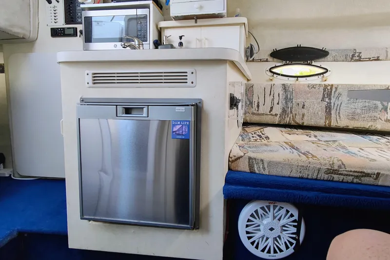 Slide: The Image of Interior of a 2001 Glastron GS 249 boat featuring a kitchenette and seating area. - 26