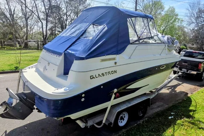 Slide: The Image of 2001 Glastron GS 249 boat on trailer with blue canopy, parked on street. - 6