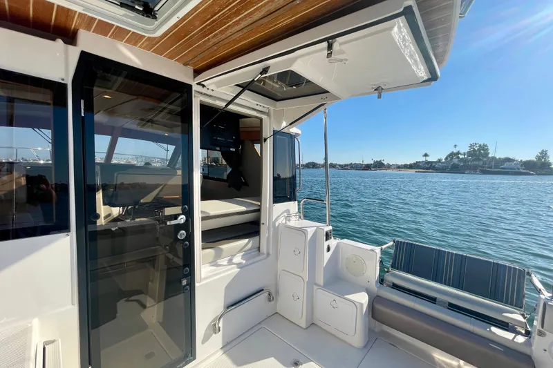 Slide: The Image of 2019 Cutwater C-302 Coupe boat interior with open door, overlooking serene water and shoreline. - 13