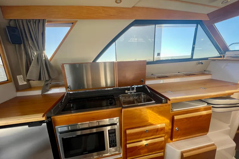 Slide: The Image of 2019 Cutwater C-302 Coupe interior kitchen with wooden cabinetry and modern appliances. - 18