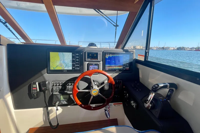 Slide: The Image of Helm of 2019 Cutwater C-302 Coupe with navigation screens and steering wheel, overlooking marina. - 25