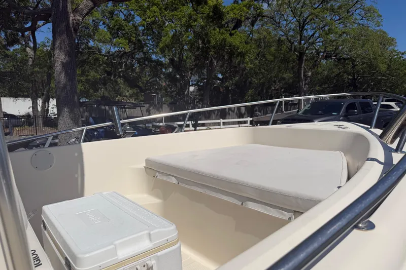Slide: The Image of 2004 Key West 186 Sportsman boat interior with seating and cooler, surrounded by trees. - 6