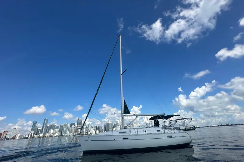 Slide: The Image of 2003 Beneteau Oceanis Clipper 331 sailboat on calm water with city skyline backdrop. - 10