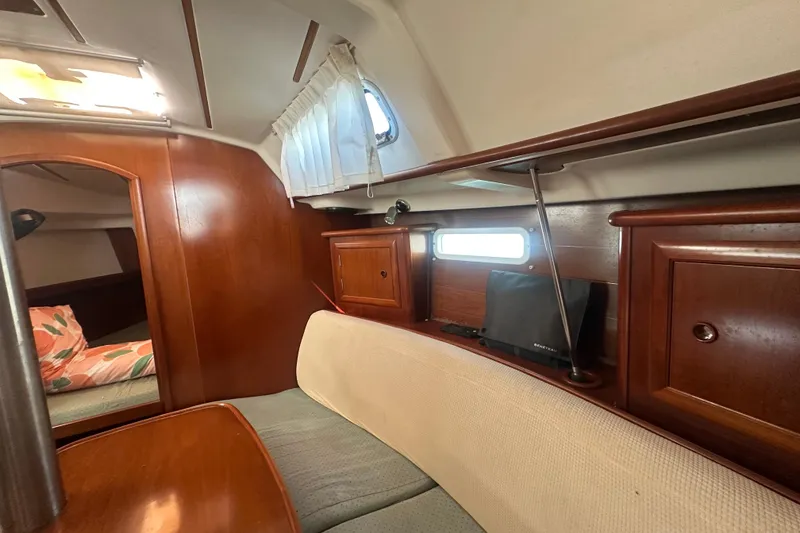 Slide: The Image of Interior of 2003 Beneteau Oceanis Clipper 331, featuring wood cabinetry and cozy seating area. - 65