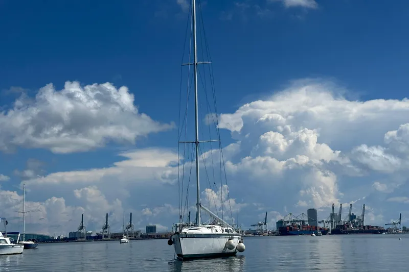 Slide: The Image of 2003 Beneteau Oceanis Clipper 331 sailboat in a harbor under a cloudy sky. - 7
