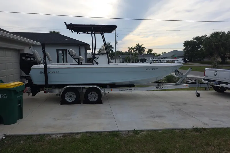 The Image of 2025 Savannah 210X boat on trailer, parked in driveway beside a house. - 0