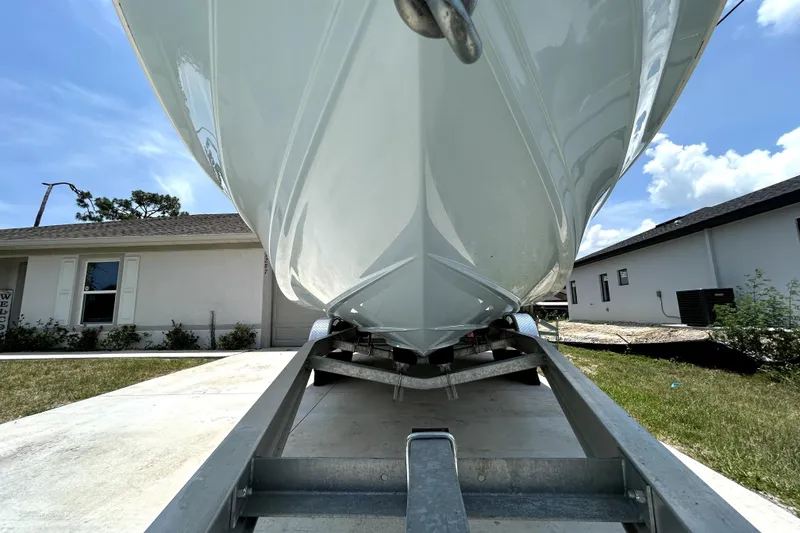 Slide: The Image of 2025 Savannah 210X boat on trailer, parked in residential driveway under clear sky. - 12