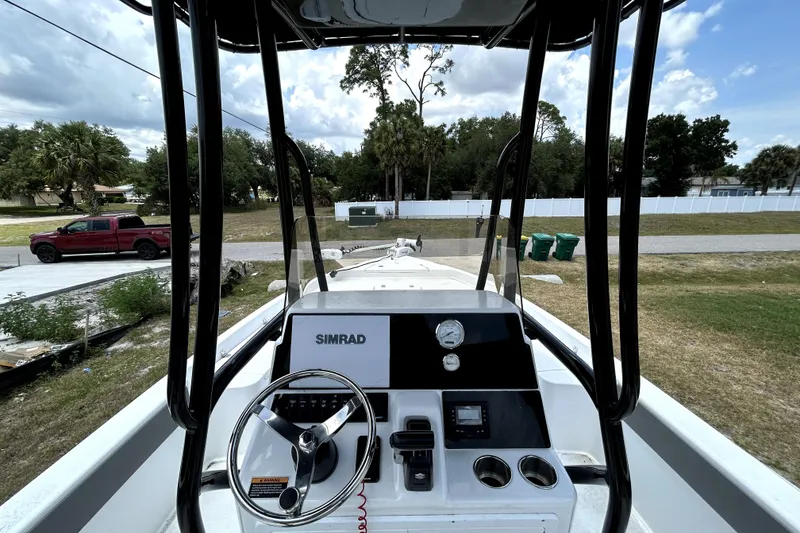 Slide: The Image of 2025 Savannah 210X boat dashboard with steering wheel and Simrad display, parked outdoors. - 18