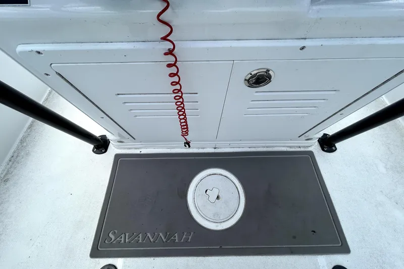 Slide: The Image of 2025 Savannah 210X boat deck with storage compartment and safety cord. - 26