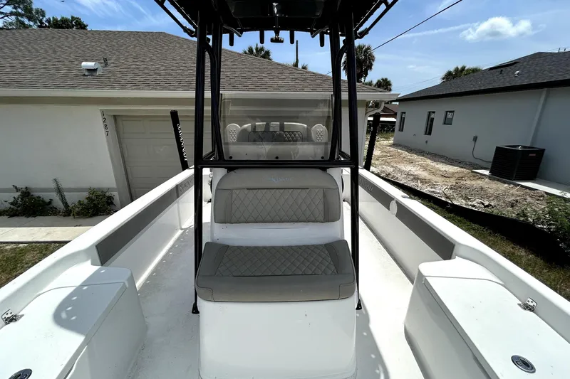 Slide: The Image of 2025 Savannah 210X boat interior with cushioned seating and console, parked near residential homes. - 42