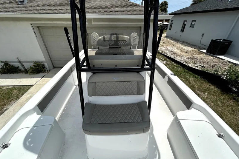Slide: The Image of 2025 Savannah 210X boat interior with cushioned seating and console, parked near a garage. - 43