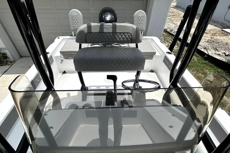Slide: The Image of 2025 Savannah 210X boat interior with steering wheel and seating, parked near a garage. - 47