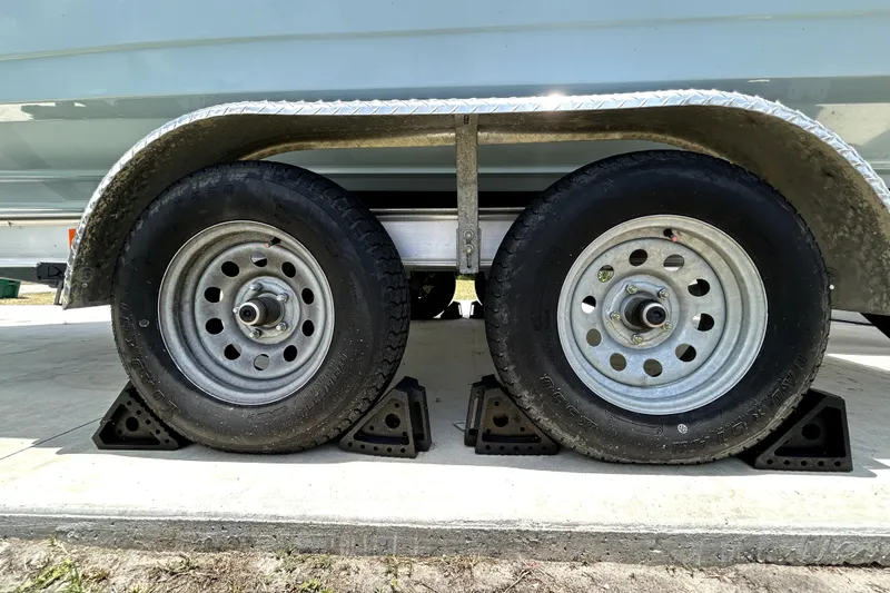 Slide: The Image of Trailer wheels of a 2025 Savannah 210X, secured with wheel chocks on concrete. - 61
