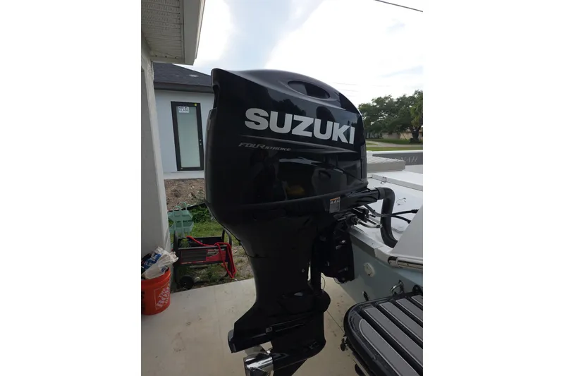 Slide: The Image of Suzuki outboard motor on 2025 Savannah 210X boat, parked outdoors. - 7