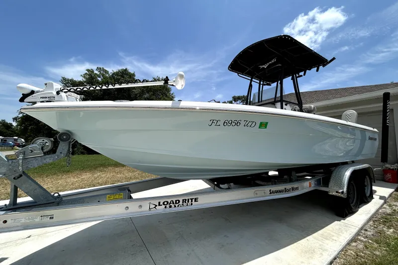 Slide: The Image of 2025 Savannah 210X boat on trailer, featuring Minn Kota motor, under clear blue sky. - 9