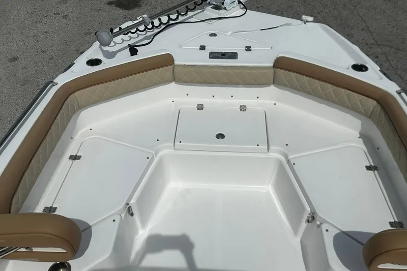 Slide: The Image of 2024 NauticStar 211 Hybrid boat interior with tan cushioned seating and storage compartments. - 10