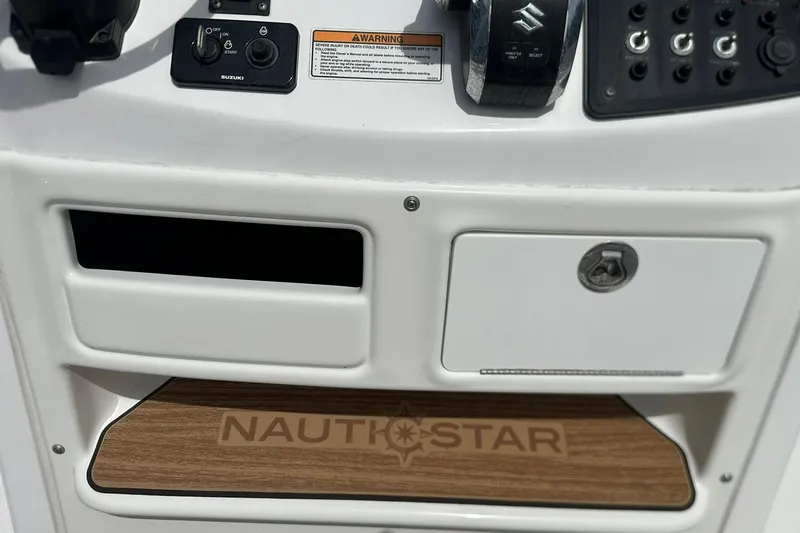 Slide: The Image of 2024 NauticStar 211 Hybrid boat dashboard with controls and logo. - 21
