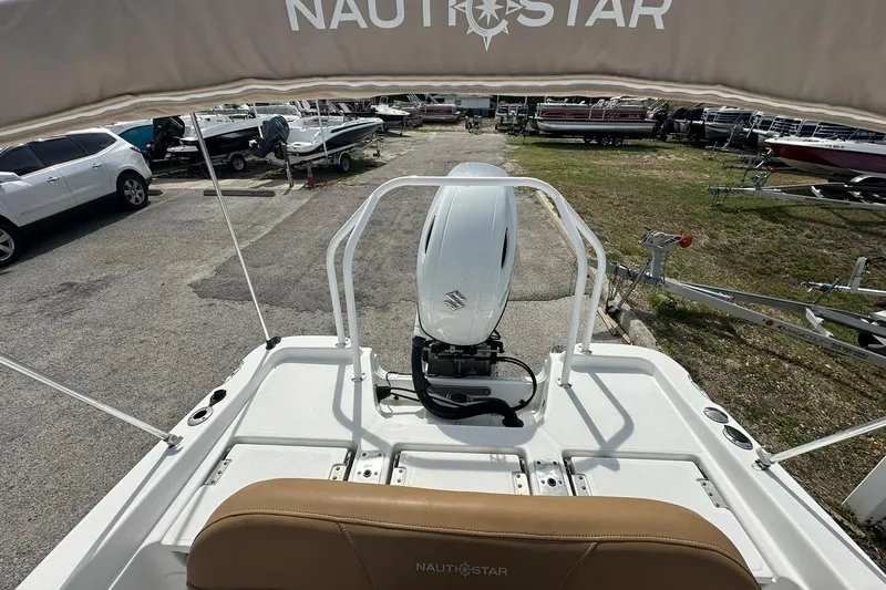 Slide: The Image of 2024 NauticStar 211 Hybrid boat with Suzuki outboard motor in a marina setting. - 25