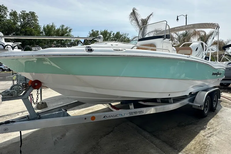 Slide: The Image of 2024 NauticStar 211 Hybrid boat on trailer, featuring sleek design and mint green hull. - 3