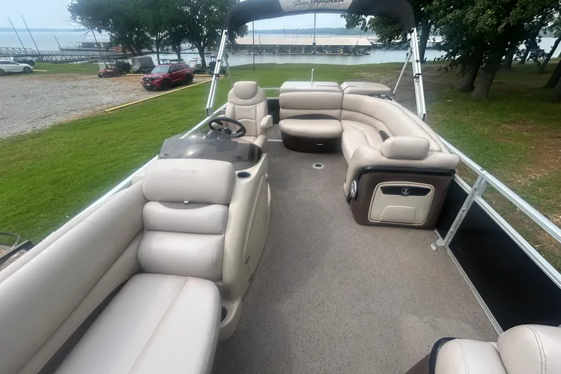 Slide: The Image of 2014 Regency 220 DL3 pontoon boat with spacious seating, docked by a scenic lakeside. - 10