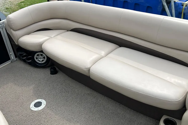 Slide: The Image of Luxurious seating on a 2014 Regency 220 DL3 pontoon boat, featuring beige upholstery and cup holders. - 12