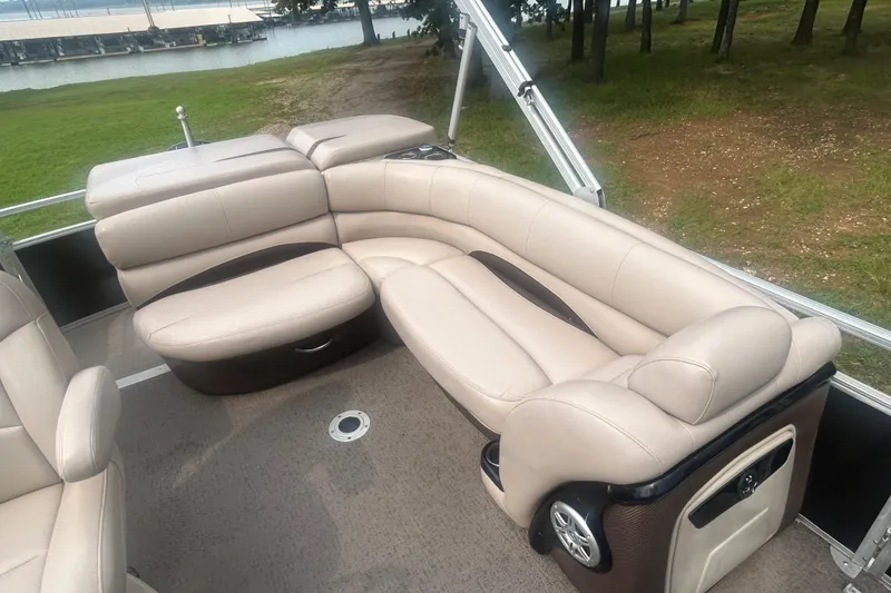 Slide: The Image of Luxurious seating on 2014 Regency 220 DL3 pontoon boat, near a scenic lakeside. - 14