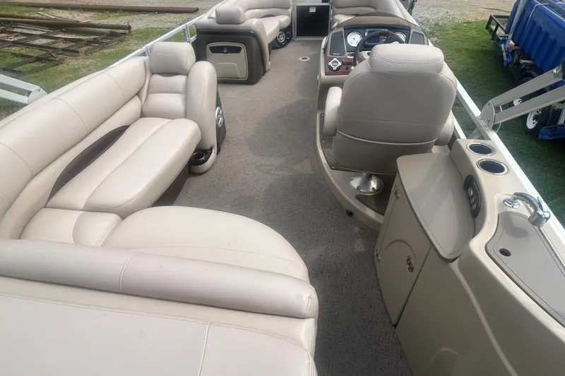 Slide: The Image of 2014 Regency 220 DL3 pontoon boat interior with beige seating and helm. - 19
