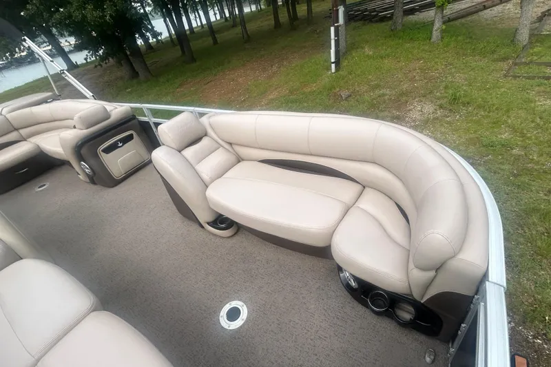 Slide: The Image of 2014 Regency 220 DL3 pontoon boat with beige seating, docked near a wooded shoreline. - 9