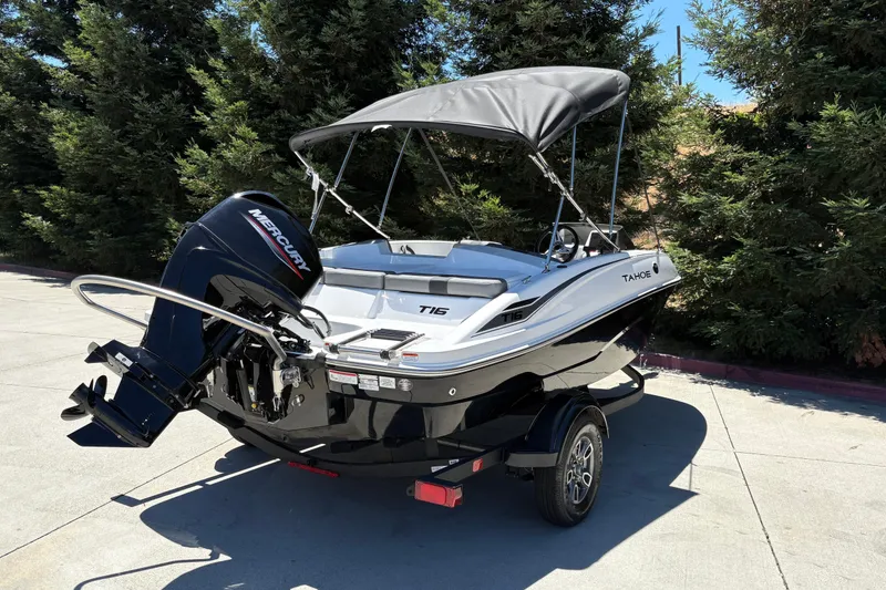Slide: The Image of 2026 Tahoe T16 boat with Mercury engine, parked on a trailer, surrounded by trees. - 9