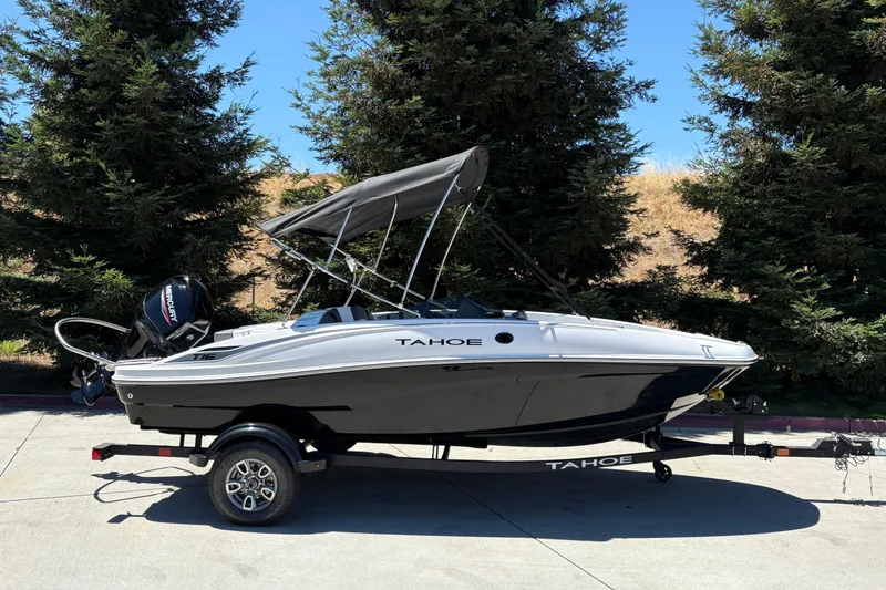 The Image of 2026 Tahoe T16 boat with canopy on trailer, parked outdoors near trees. - 0