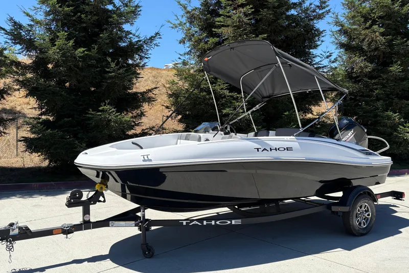 Slide: The Image of 2026 Tahoe T16 boat with canopy on trailer, parked outdoors near trees. - 3