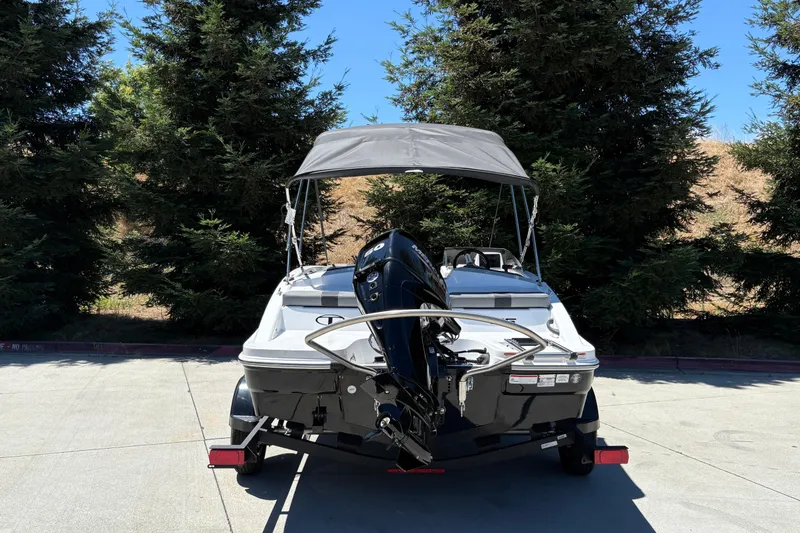Slide: The Image of 2026 Tahoe T16 boat with canopy, parked outdoors near trees. - 10