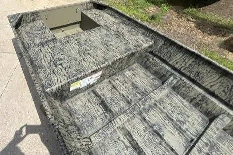 Slide: The Image of 2026 Tracker Grizzly 15 Jon boat with camouflage pattern on concrete surface. - 2