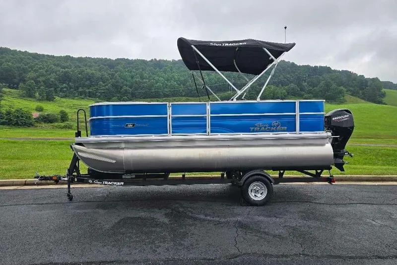 Slide: The Image of 2026 Sun Tracker Party Barge 18 DLX pontoon boat on trailer, scenic background. - 3