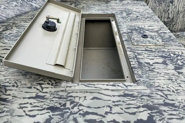 Slide: The Image of 2026 Tracker Grizzly 1648 Utility boat with open storage compartment on camo-patterned deck. - 14
