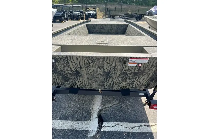 Slide: The Image of 2026 Tracker Grizzly 1648 Utility boat with camouflage design in a parking lot. - 3
