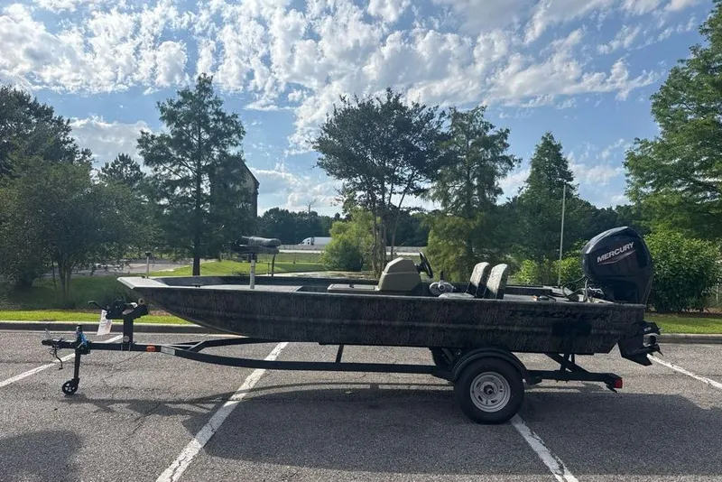 The Image of 2026 Tracker Grizzly 1754 SC boat on trailer, parked outdoors under a partly cloudy sky. - 0