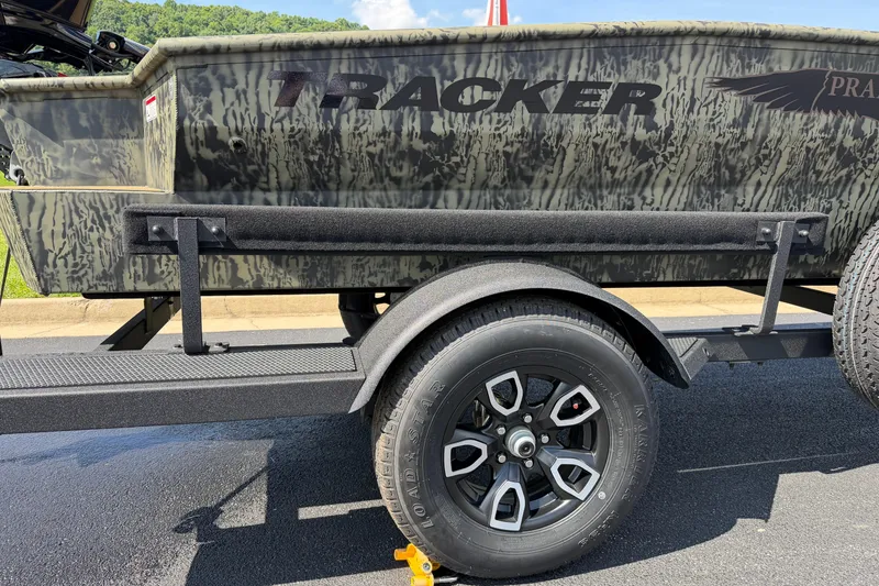 Slide: The Image of 2026 Tracker Grizzly 1650 T Prairie Wings Edition boat on trailer, camo design, sunny day. - 9
