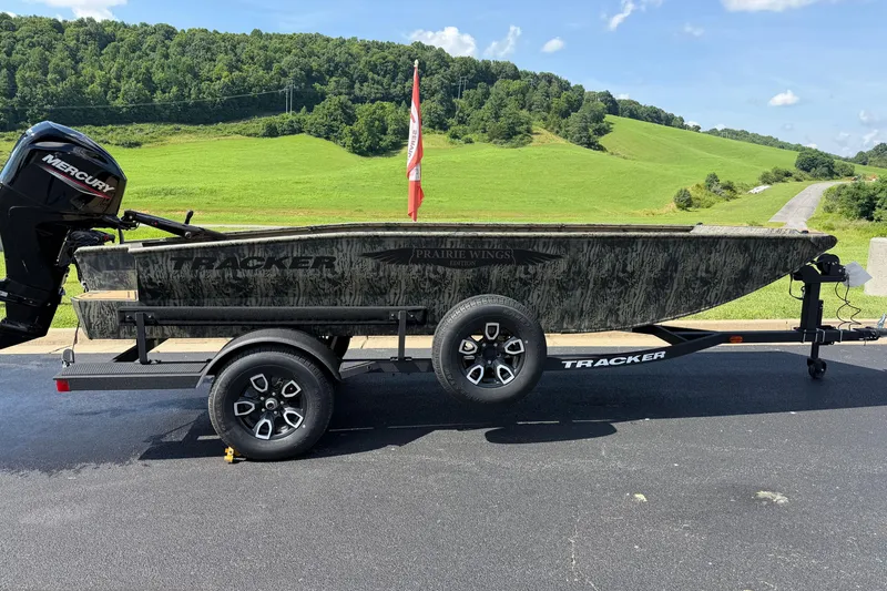 Slide: The Image of 2026 Tracker Grizzly 1650 T Prairie Wings Edition boat on trailer, scenic countryside background. - 2