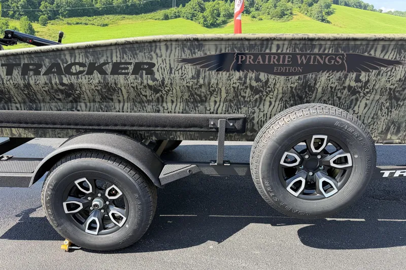 Slide: The Image of 2026 Tracker Grizzly 1650 T Prairie Wings Edition boat on trailer, camo design, outdoor setting. - 13