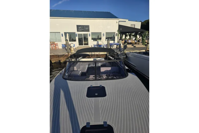 Slide: The Image of 2016 VanDutch 40 yacht docked near a waterfront restaurant under clear blue skies. - 2