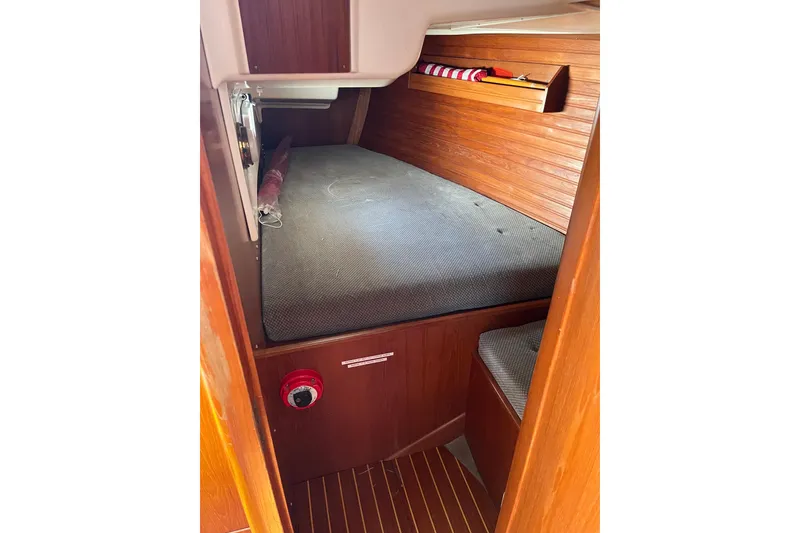 Slide: The Image of 1986 Wauquiez Petorine cabin interior with wooden paneling and cushioned berth. - 14