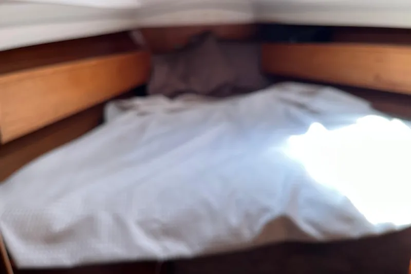 Slide: The Image of Cozy cabin interior of 1986 Wauquiez Petorine sailboat with wooden accents and bedding. - 18